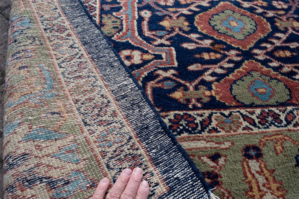 A large hand-knotted antique Persian Mahal carpet featuring intricate floral palmette patterns in navy, terracotta, and soft green across a dark blue field. View IV