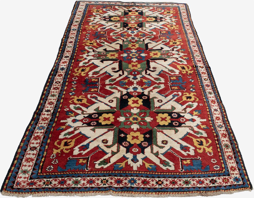 An antique hand-knotted Caucasian Eagle Kazak wool rug featuring repeating ivory geometric eagle medallions on a vibrant red field with a patterned border. View IV