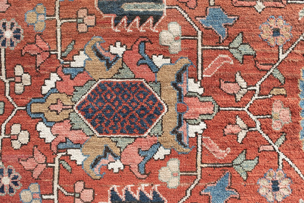 An antique Persian Heriz wool carpet featuring a central geometric medallion on a terracotta field surrounded by a dark navy decorative border. View VII