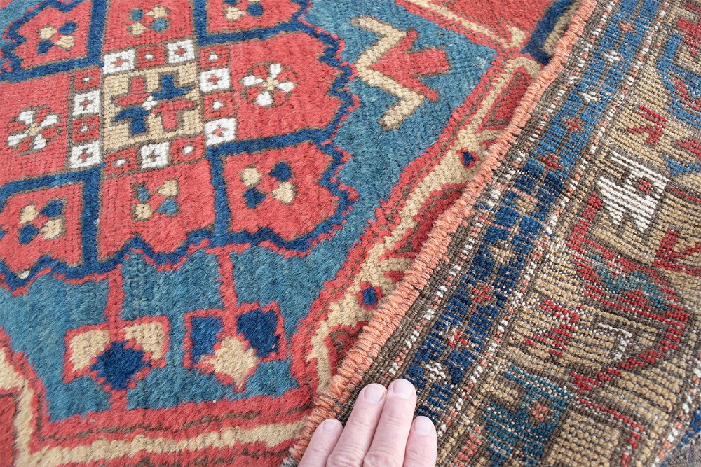 A long hand-knotted antique Heriz runner rug with geometric medallions in red, blue, turquoise, and cream tones. View V