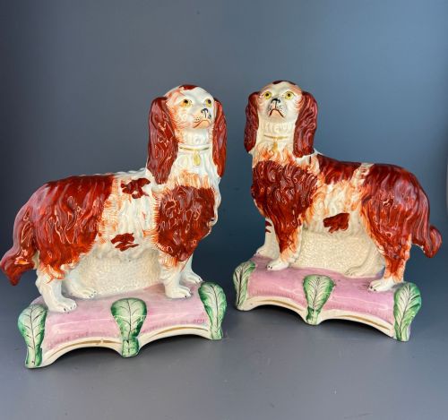 fig 1. A pair of 19th-century Victorian Staffordshire earthenware spaniel dogs painted in russet brown and white standing on pink cushion bases.