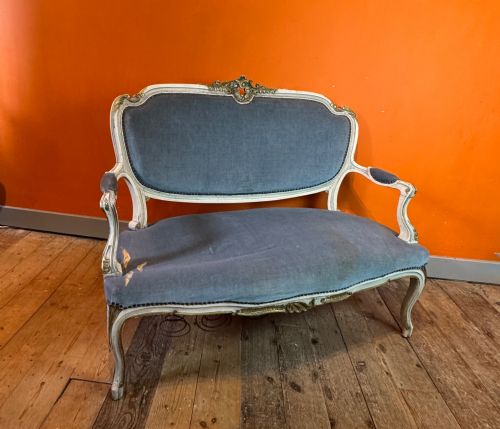 fig 1. An antique Louis XV style two-seat settee featuring a cream painted and carved wooden frame with gilt accents, cabriole legs, and blue-grey fabric upholstery.