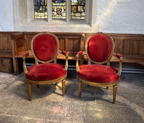 fig 1. A pair of 19th-century Louis XVI style giltwood armchairs featuring crimson red velvet upholstery and carved medallion backs.