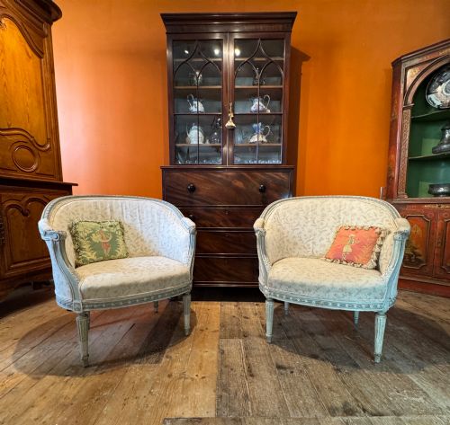 fig 1. A pair of French tub armchairs featuring distressed cream painted carved wooden frames and light floral upholstery.