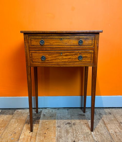 fig 1. A Sheraton style satinwood side table featuring two crossbanded drawers with round brass pulls and square tapered legs.