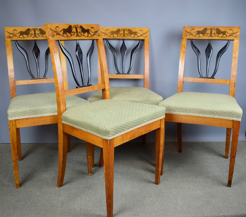 Set of four Biedermeier inlaid satinwood dining chairs with lion decoration