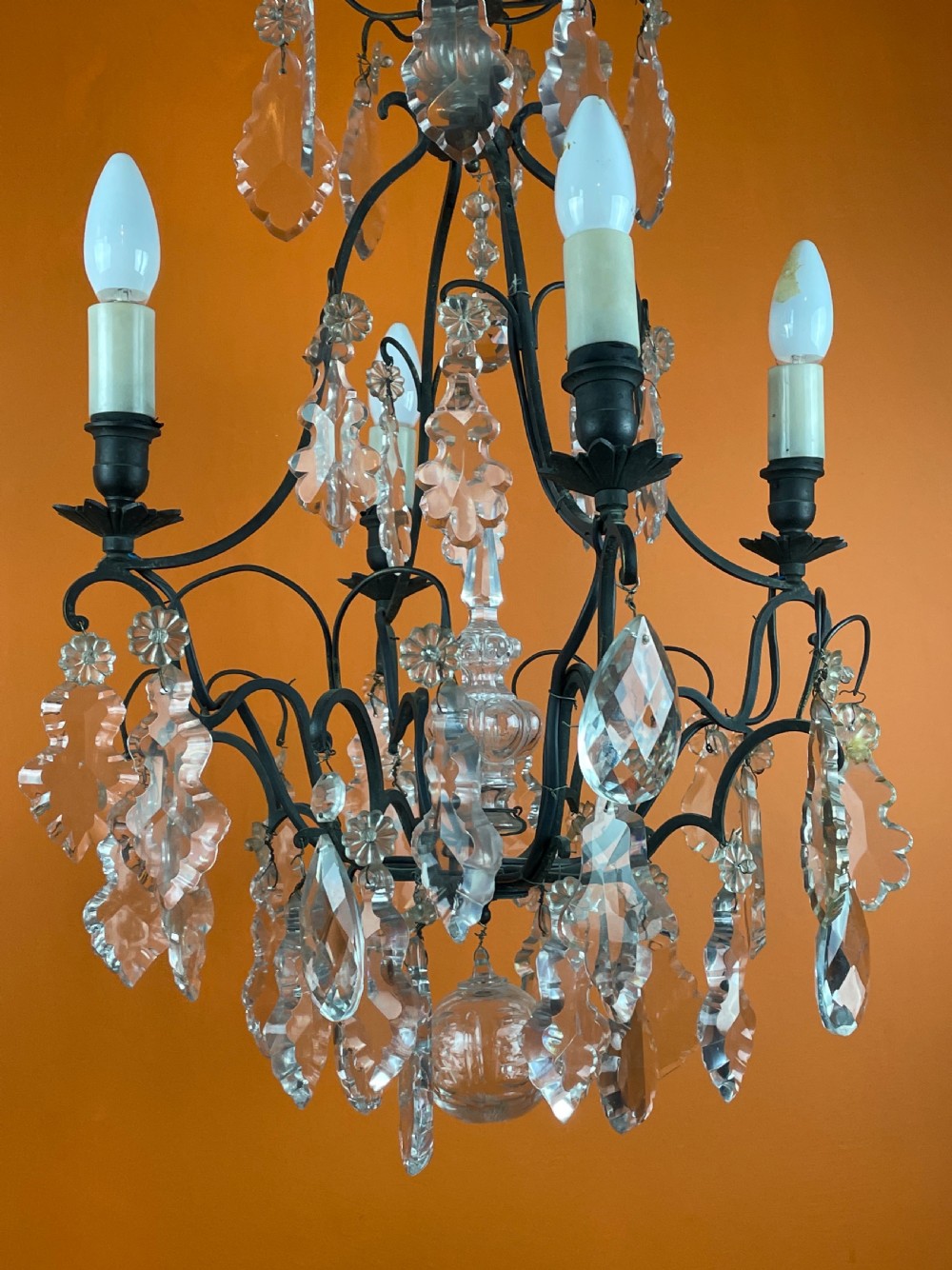 A French style cut glass cage chandelier featuring a dark wrought iron frame decorated with clear glass drops, rosettes, and candle-style bulb sockets. View II