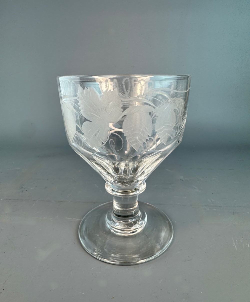 A clear Regency period glass rummer featuring wheel-engraved foliate decoration, a short knopped stem, and a sturdy circular foot.