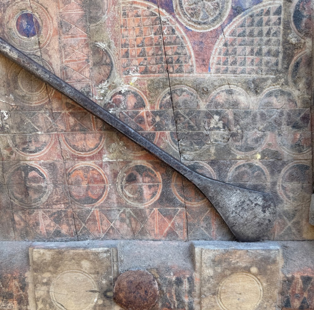A hand-forged dark steel spearhead with a defined central ridge attached to a slender wooden shaft. View II