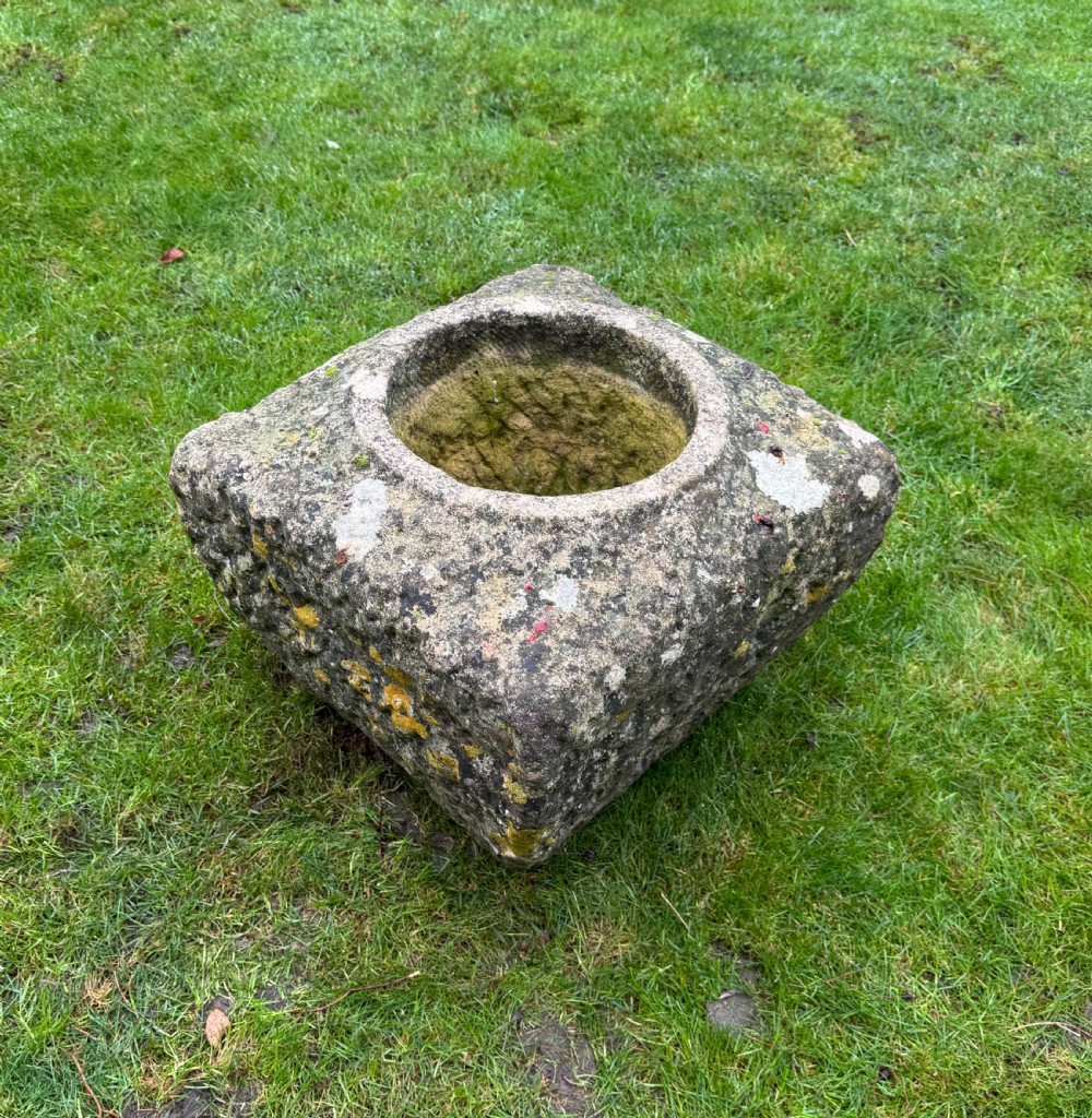 A square carved weathered stone planter with a circular central recess and rusticated hand-chiselled exterior surfaces displaying natural moss growth. View V