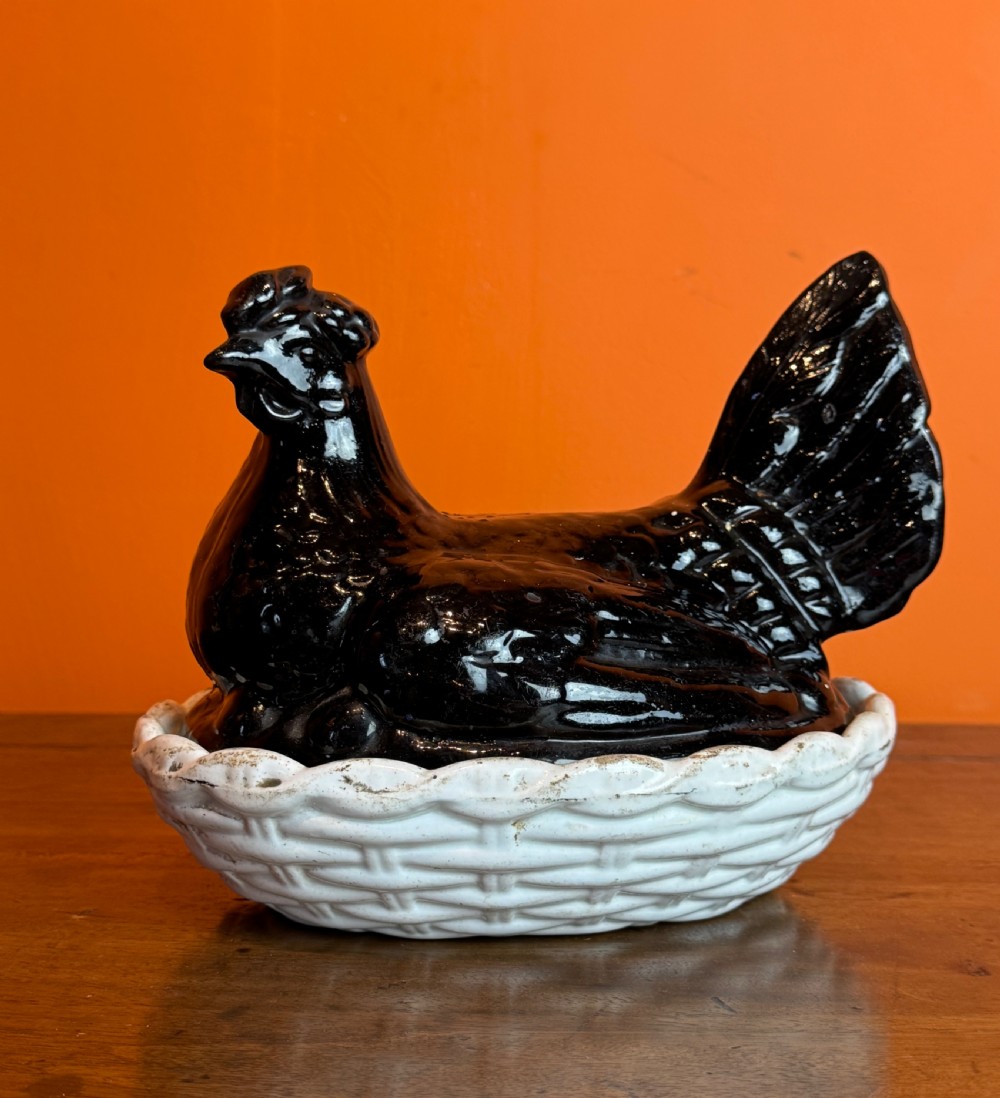 A Victorian Staffordshire Jackfield ceramic covered dish featuring a black glazed hen resting atop a white basketweave earthenware base. View II