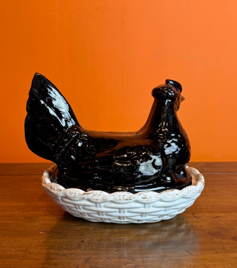 A Victorian Staffordshire Jackfield ceramic covered dish featuring a black glazed hen resting atop a white basketweave earthenware base. View V