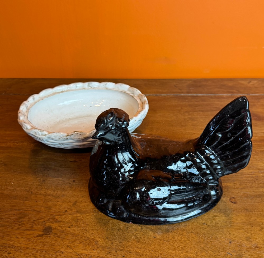 A Victorian Staffordshire Jackfield ceramic covered dish featuring a black glazed hen resting atop a white basketweave earthenware base. View VI