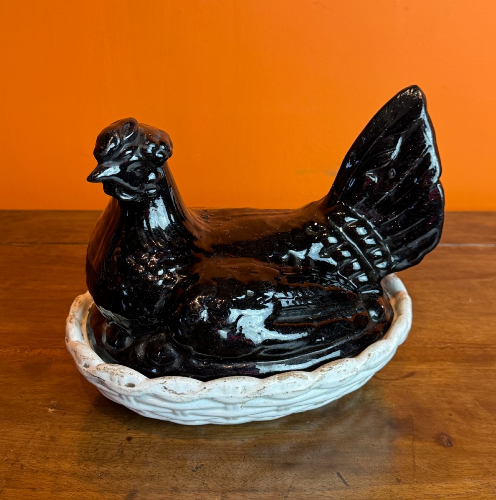 A Victorian Staffordshire Jackfield ceramic covered dish featuring a black glazed hen resting atop a white basketweave earthenware base. View VII