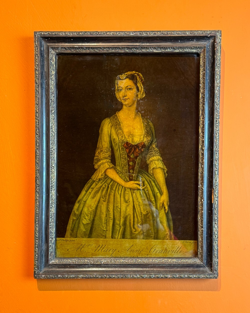 An 18th-century reverse glass mezzotint portrait depicting a woman in a yellow dress set within a dark moulded frame. View IV