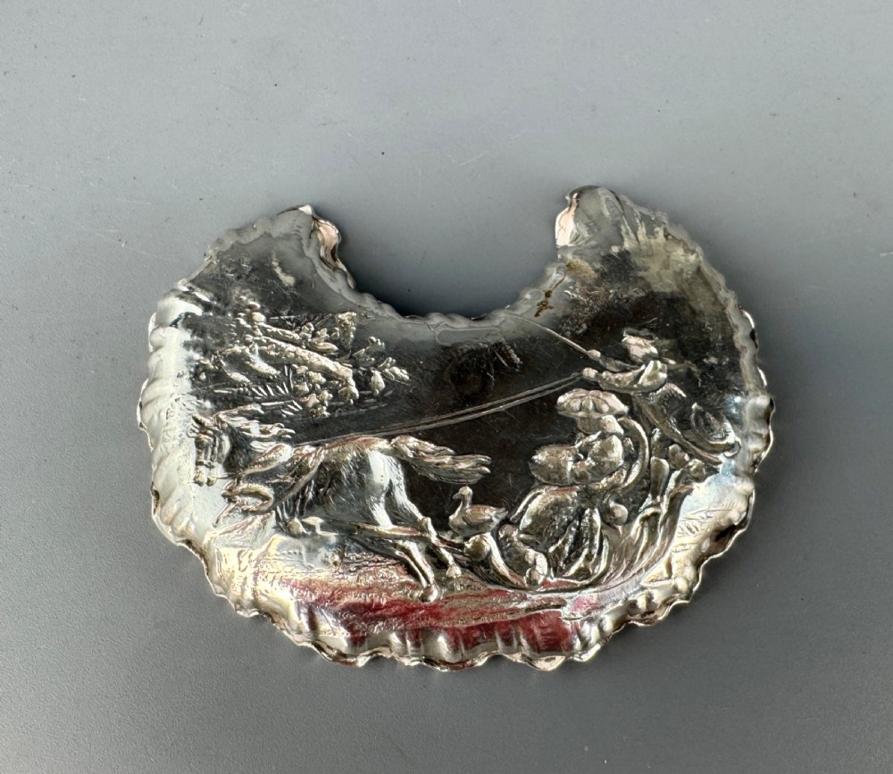 A late Victorian crescent-shaped sterling silver trinket dish with embossed repousse figural scenes and a fluted border. View II