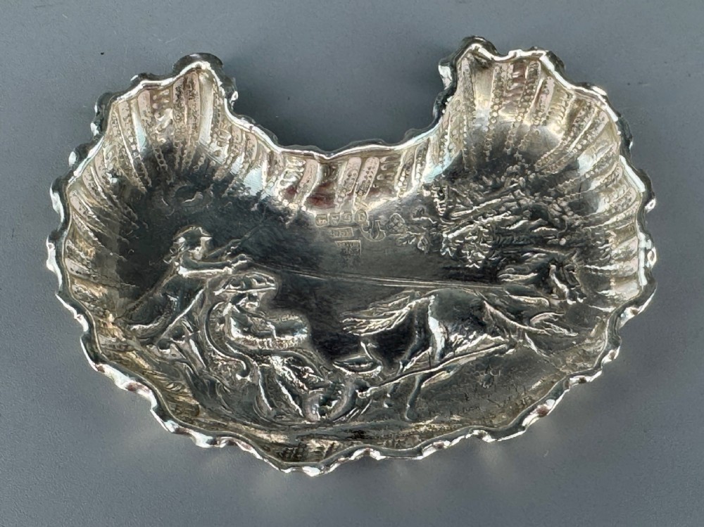 A late Victorian crescent-shaped sterling silver trinket dish with embossed repousse figural scenes and a fluted border. View IV