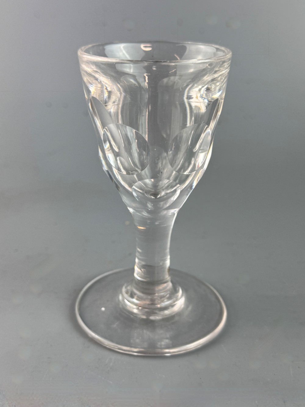 A clear Victorian deception glass featuring a thick-walled thumb-cut bowl, short stem, and circular foot.