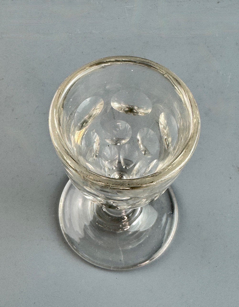 A clear Victorian glass featuring thumb-cut facets around the lower bowl, a short solid stem, and a wide flat base. View IV