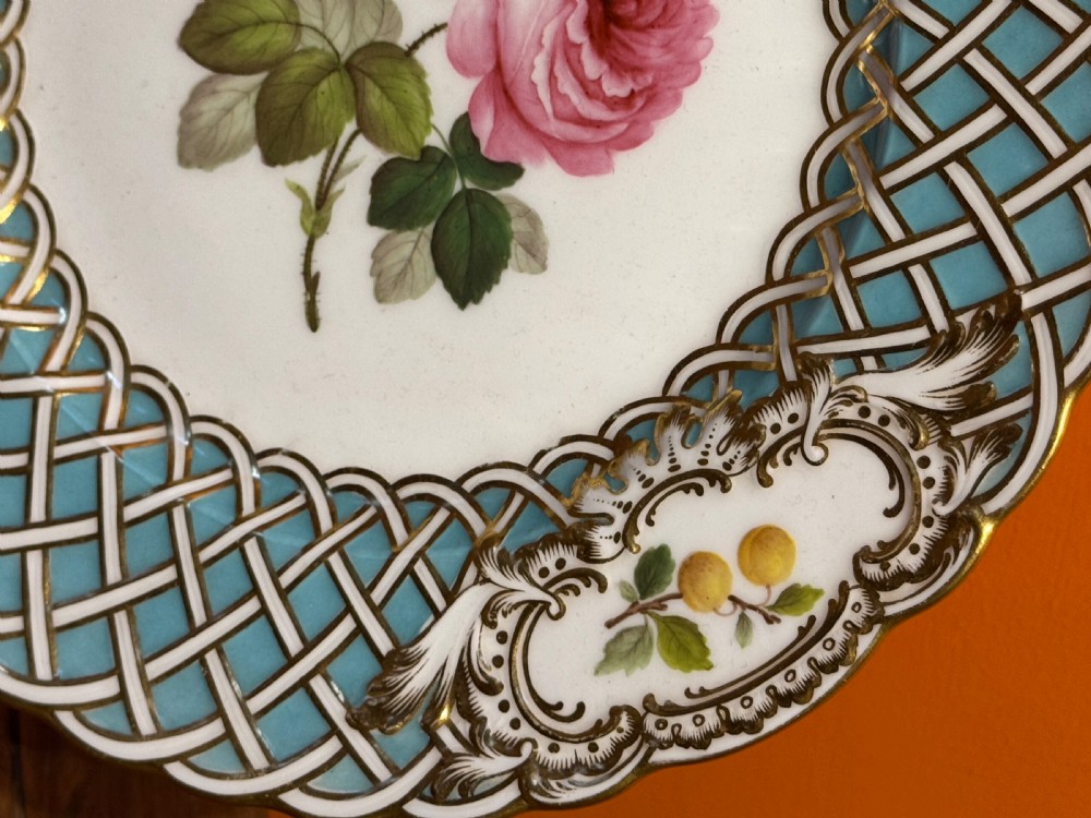 A circular Victorian Minton porcelain plate featuring a central hand-painted pink rose surrounded by a turquoise basketweave border and gilded scroll cartouches displaying fruit motifs. View III
