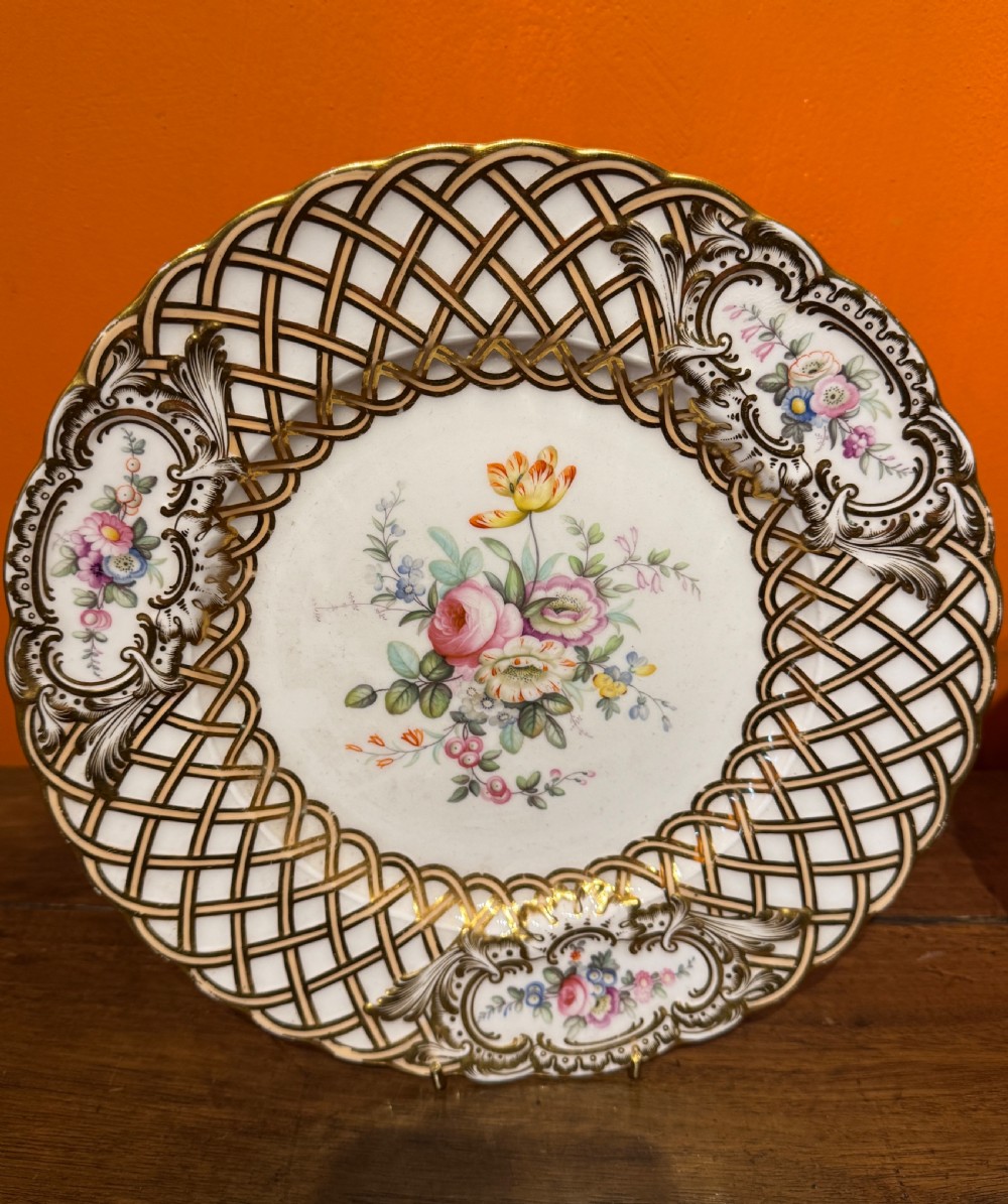 A circular Minton porcelain plate featuring a gilded basketweave border, rococo scroll cartouches, and hand-painted central floral bouquet on a white background. View II
