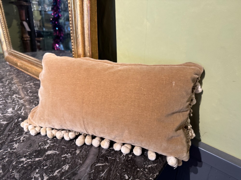 A rectangular antique French tapestry cushion with floral needlepoint detail in beige and pink tones, trimmed with a fringe and pom-pom border. View II