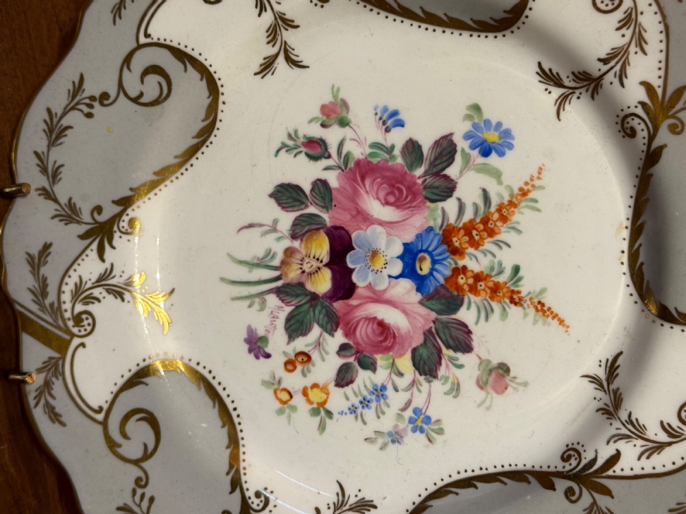 A pair of Victorian Coalport porcelain dessert plates featuring scalloped gilded rims, grey borders with gold foliage, and central hand-painted floral bouquets. View IV