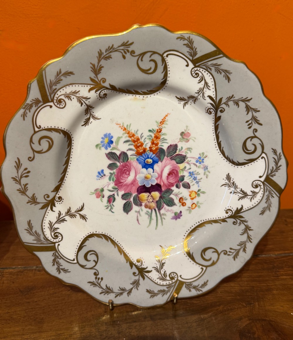 A pair of Victorian Coalport porcelain dessert plates featuring scalloped gilded rims, grey borders with gold foliage, and central hand-painted floral bouquets. View VI