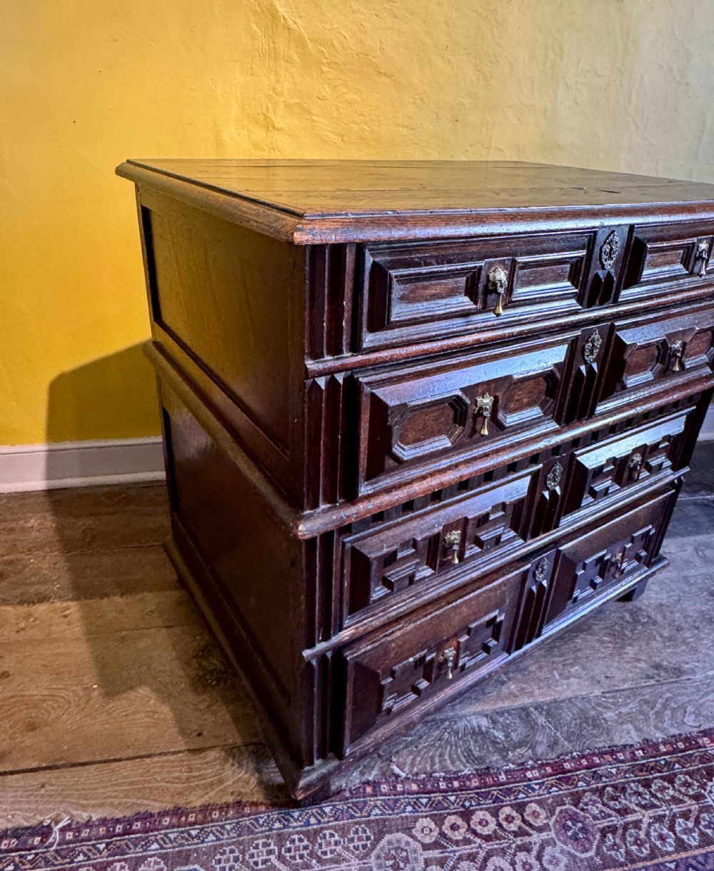 A 17th-century Charles II dark oak two-part chest of drawers featuring geometric mitred drawer mouldings and brass teardrop handles. View IV