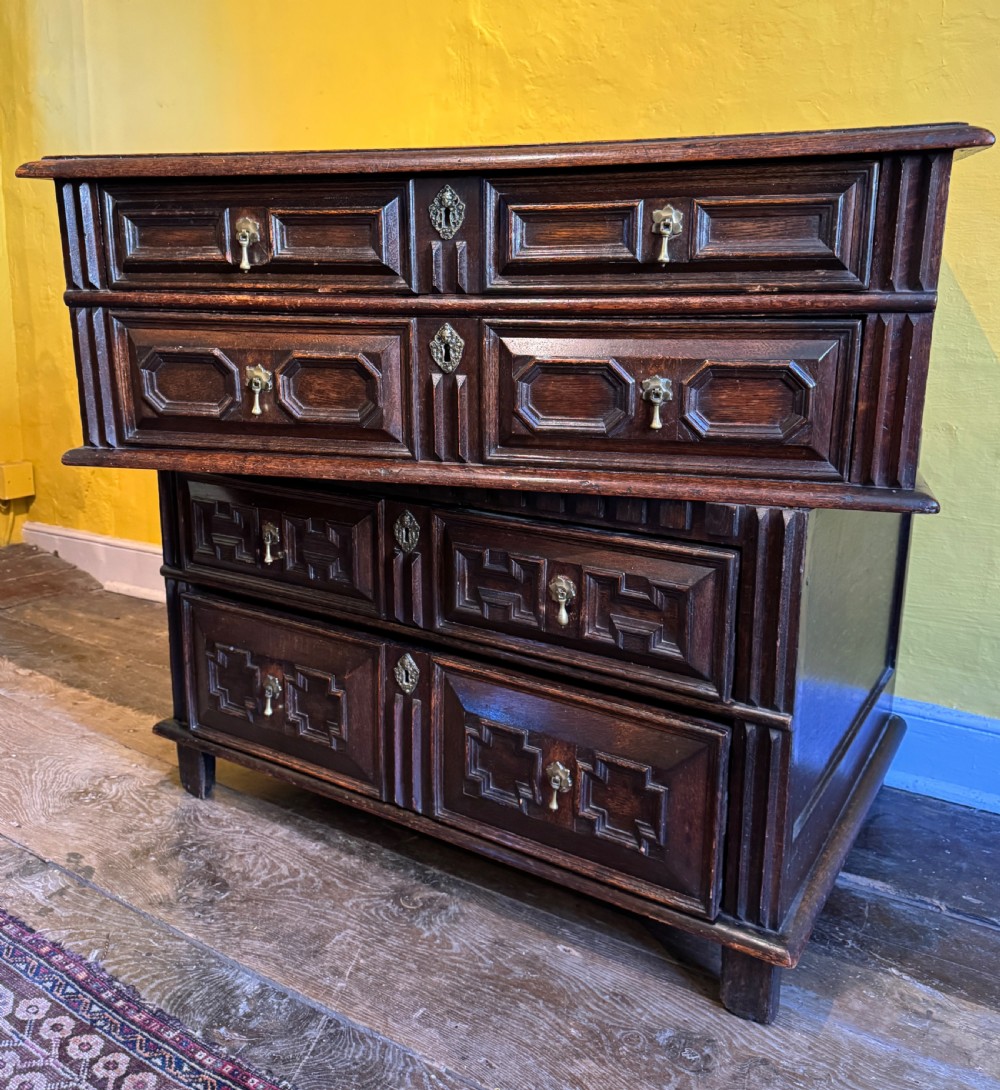 A 17th-century Charles II dark oak two-part chest of drawers featuring geometric mitred drawer mouldings and brass teardrop handles. View VI
