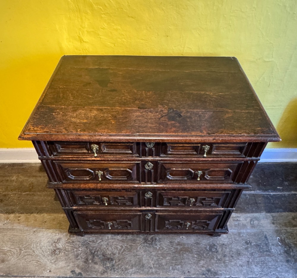 A 17th-century Charles II dark oak two-part chest of drawers featuring geometric mitred drawer mouldings and brass teardrop handles. View IX