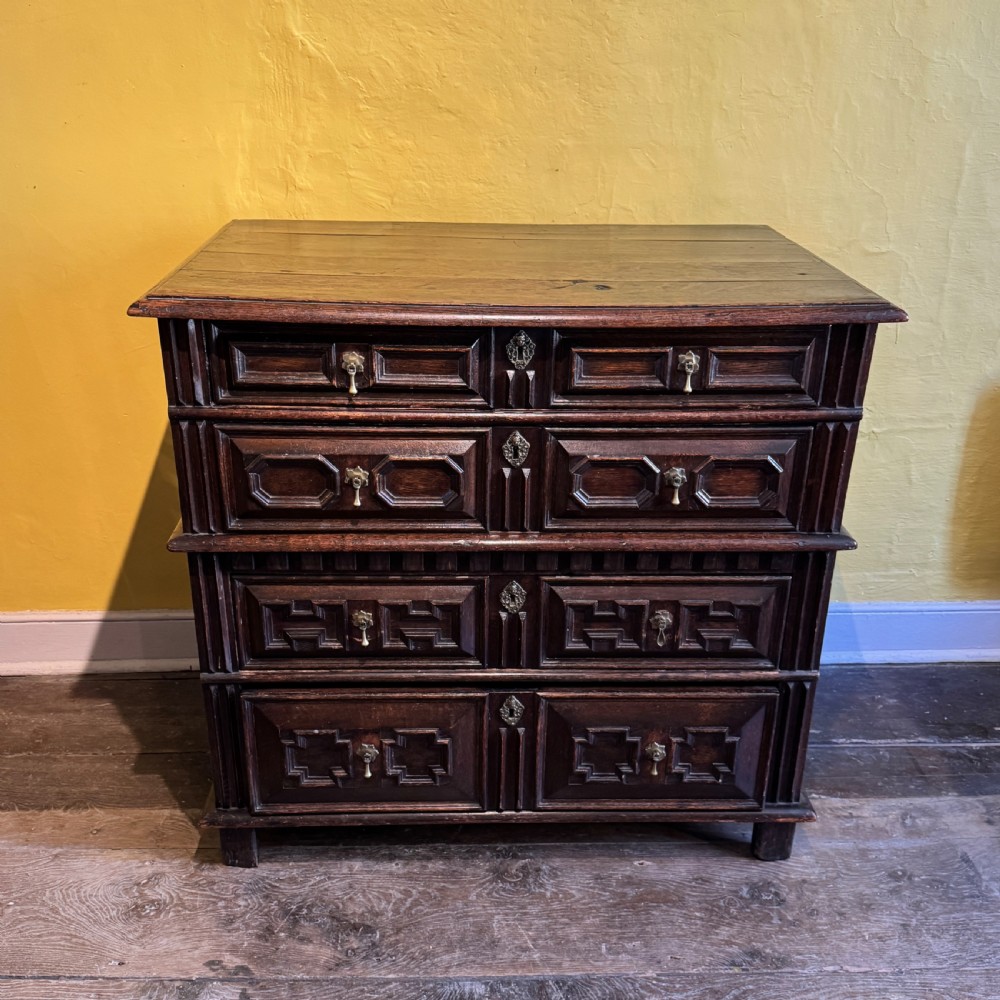 A 17th-century Charles II dark oak two-part chest of drawers featuring geometric mitred drawer mouldings and brass teardrop handles. View XII