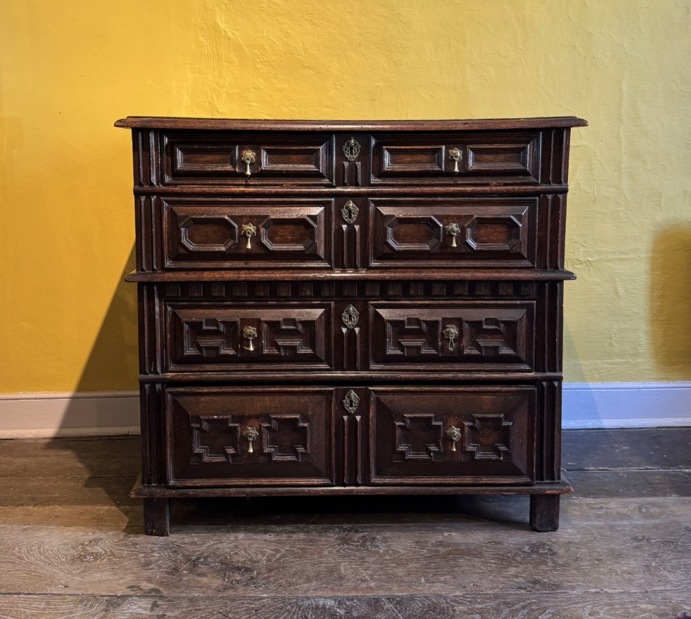 A 17th-century Charles II dark oak two-part chest of drawers featuring geometric mitred drawer mouldings and brass teardrop handles. View XIII
