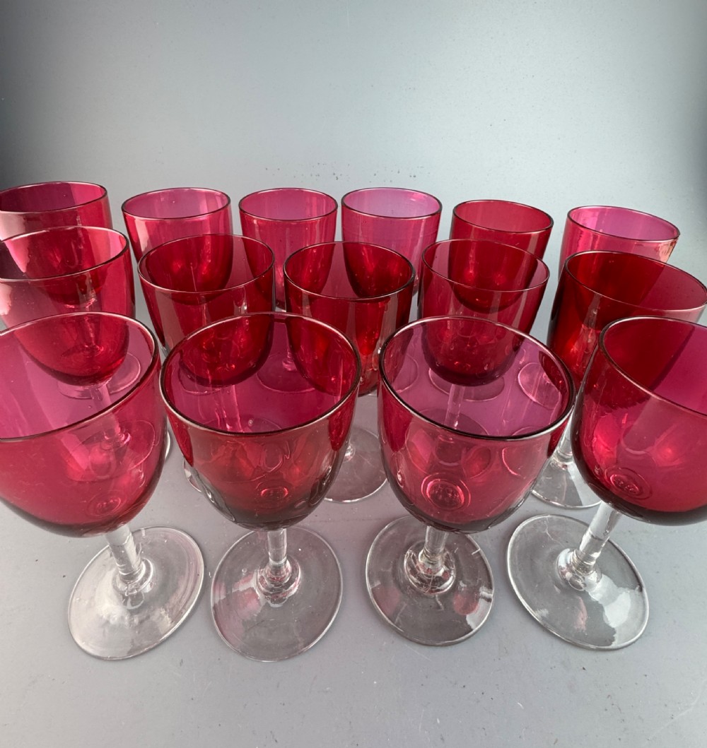 A set of fifteen Victorian wine glasses featuring cranberry-coloured glass bowls set upon clear glass stems and circular bases. View II
