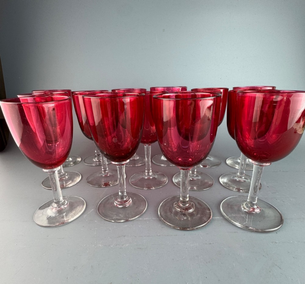 A set of fifteen Victorian wine glasses featuring cranberry-coloured glass bowls set upon clear glass stems and circular bases. View IV