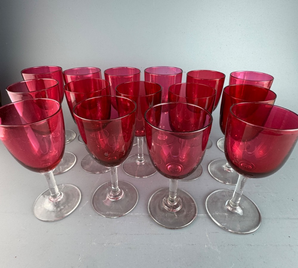 A set of fifteen Victorian wine glasses featuring cranberry-coloured glass bowls set upon clear glass stems and circular bases. View V