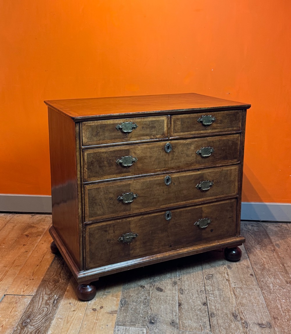 A George I walnut chest of drawers with two short over three long feather-banded drawers and brass handles.
