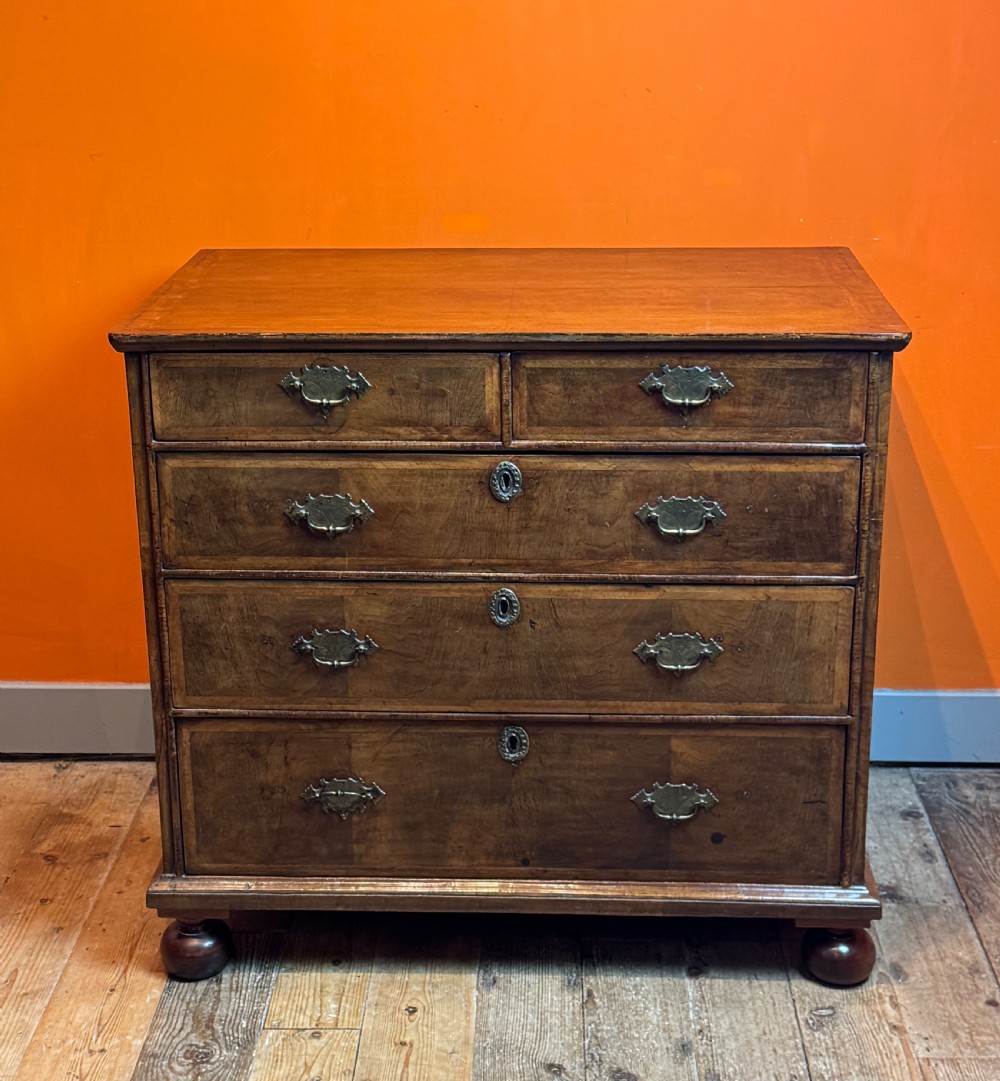 A George I walnut chest of drawers with two short over three long feather-banded drawers and brass handles. View II