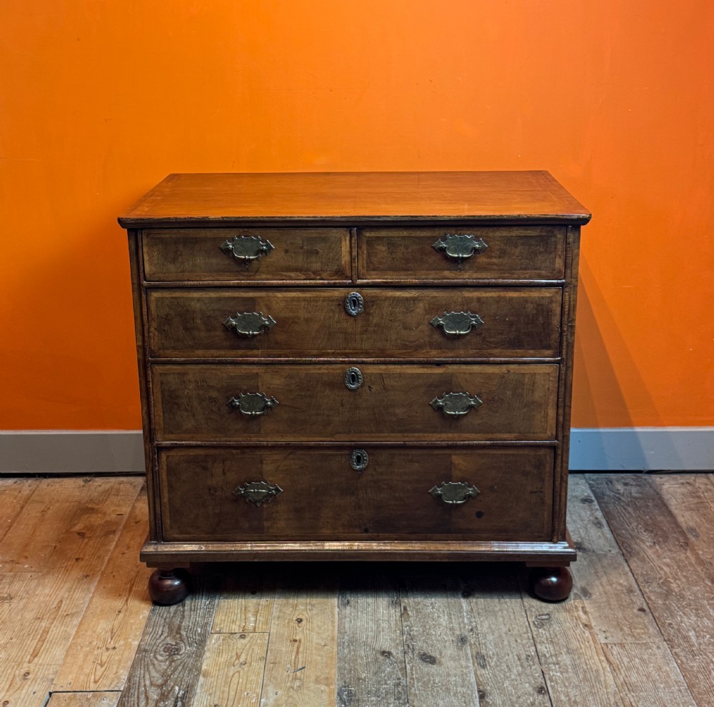 A George I walnut chest of drawers with two short over three long feather-banded drawers and brass handles. View III
