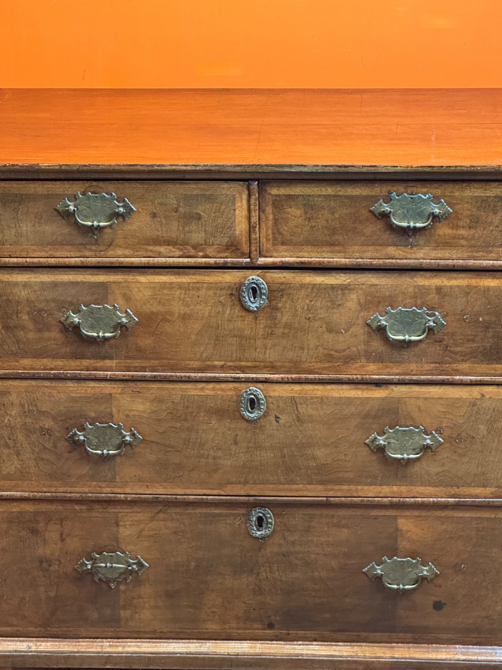 A George I walnut chest of drawers with two short over three long feather-banded drawers and brass handles. View IV