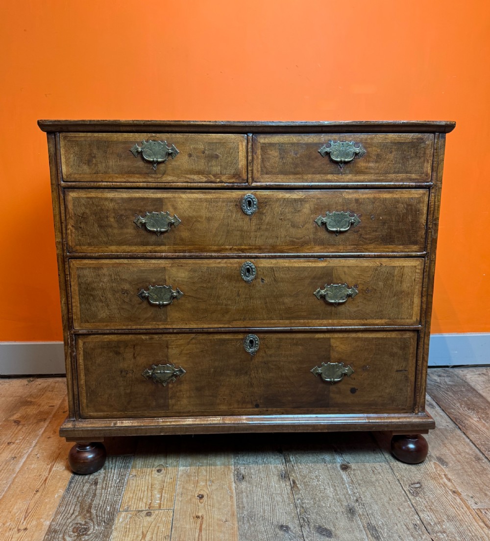 A George I walnut chest of drawers with two short over three long feather-banded drawers and brass handles. View V