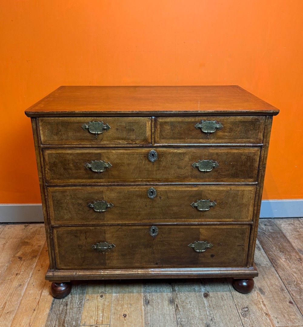 A George I walnut chest of drawers with two short over three long feather-banded drawers and brass handles. View IX