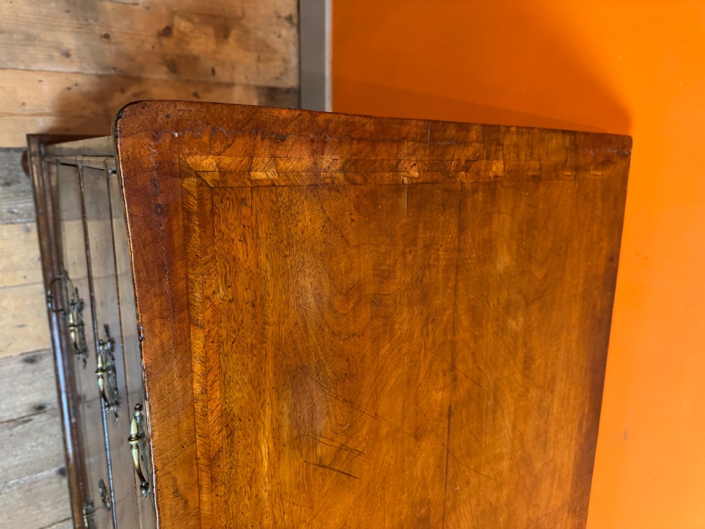 A George I walnut chest of drawers with two short over three long feather-banded drawers and brass handles. View XI