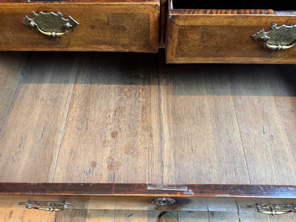 A George I walnut chest of drawers with two short over three long feather-banded drawers and brass handles. View XIII
