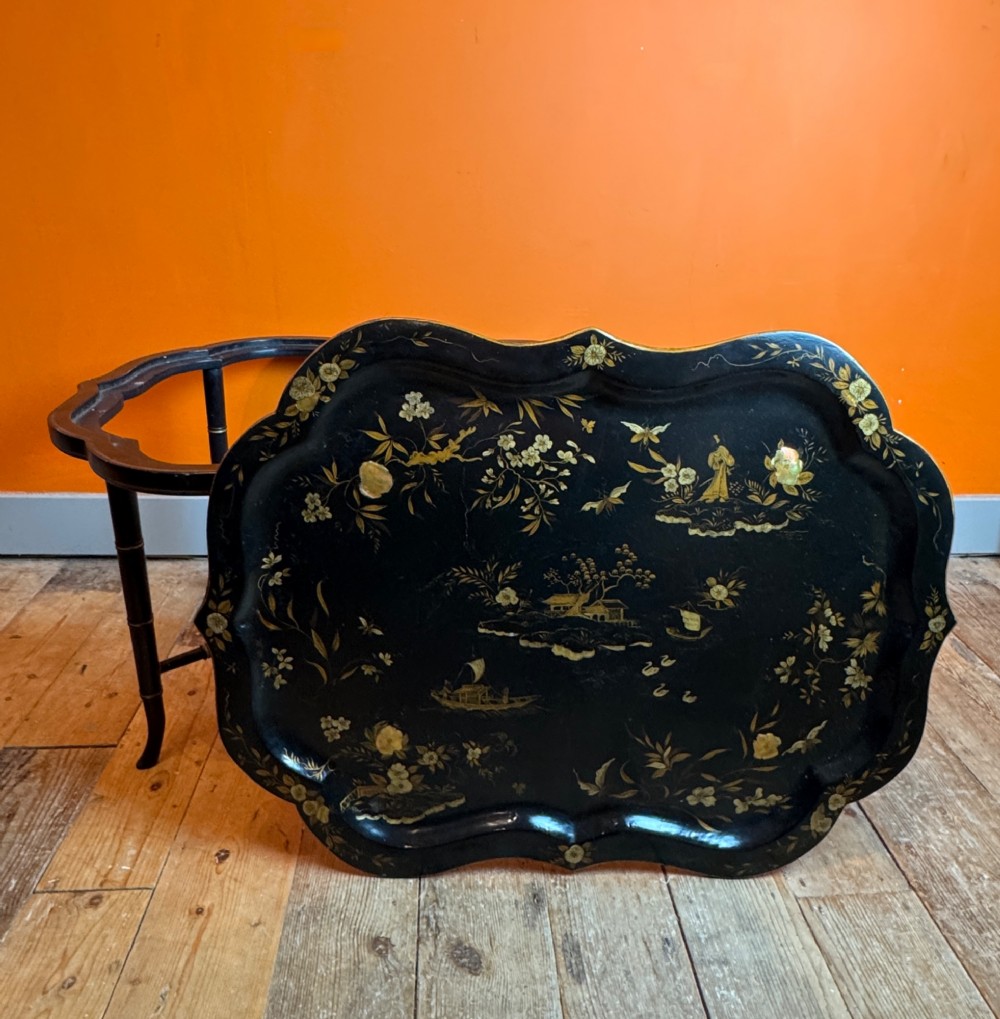 A Victorian ebonised papier-mache tray with serpentine edges and gilt Chinoiserie decoration, resting upon a turned black stand with faux bamboo legs. View III