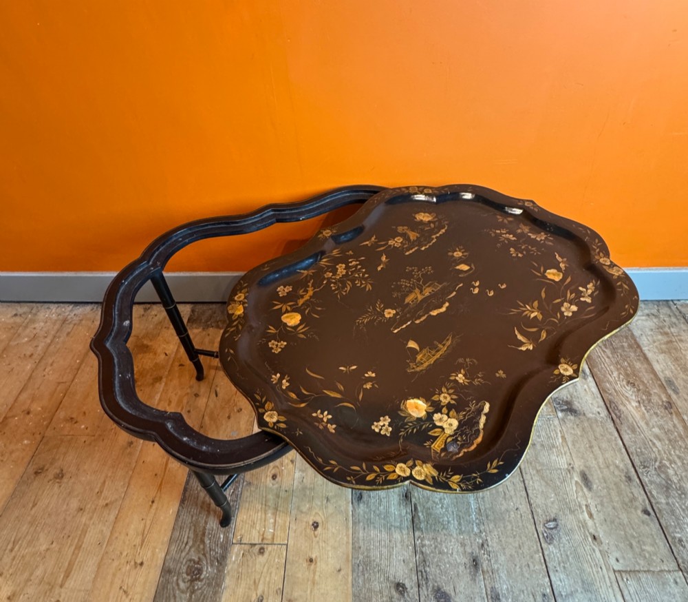 A Victorian ebonised papier-mache tray with serpentine edges and gilt Chinoiserie decoration, resting upon a turned black stand with faux bamboo legs. View IV