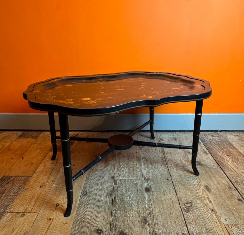 A Victorian ebonised papier-mache tray with serpentine edges and gilt Chinoiserie decoration, resting upon a turned black stand with faux bamboo legs. View V