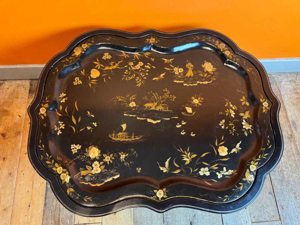 A Victorian ebonised papier-mache tray with serpentine edges and gilt Chinoiserie decoration, resting upon a turned black stand with faux bamboo legs. View IX
