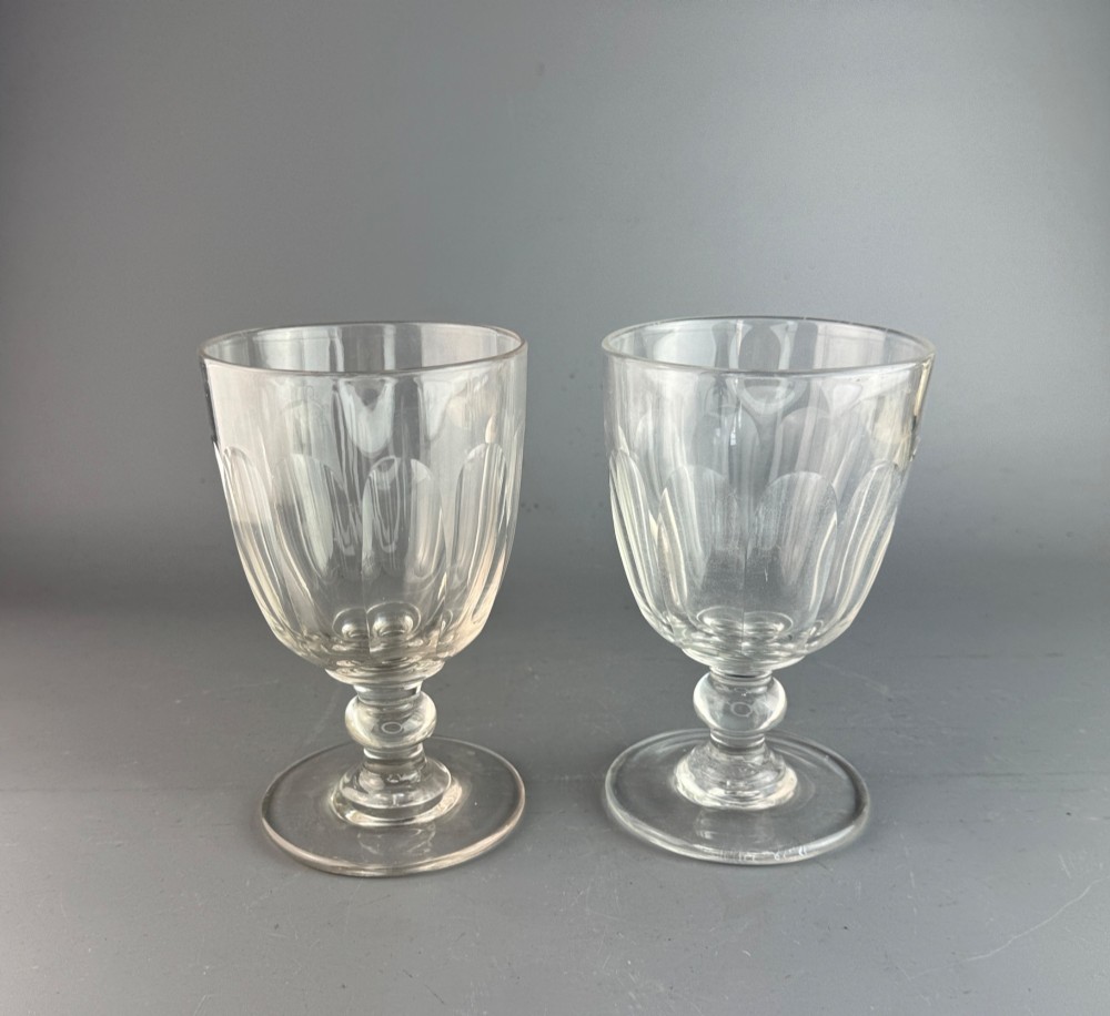 A pair of clear cut glass rummers with fluted lower bowls, short knopped stems, and broad circular bases.