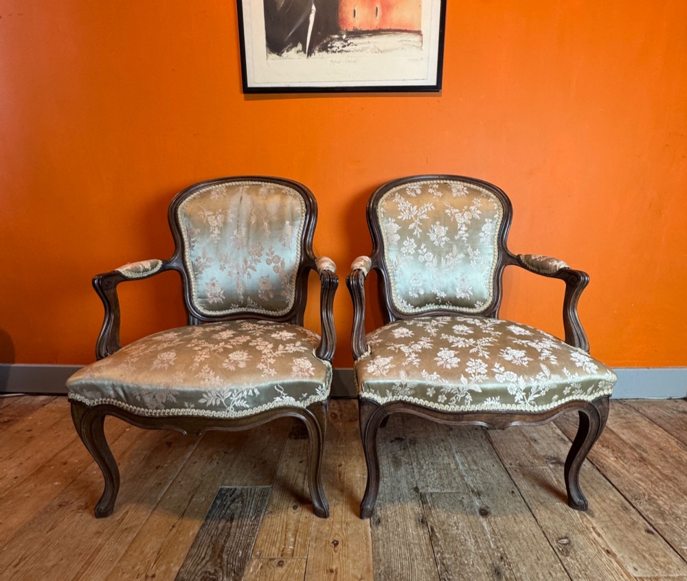 A pair of Louis XV style walnut fauteuil armchairs upholstered in sage green floral silk damask fabric featuring carved cabriole legs. View IV